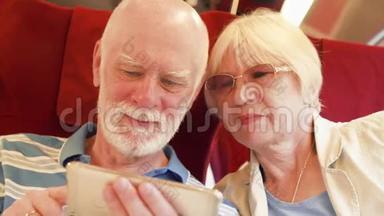 使用智能手机的高速国际列车的高级夫妇。 退休后积极的现代生活